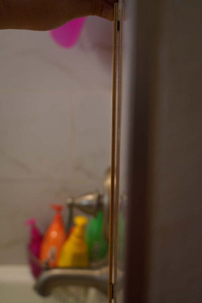 Closeup look at the gap between the ruler and an unevenly-placed tile in our guest bath and shower