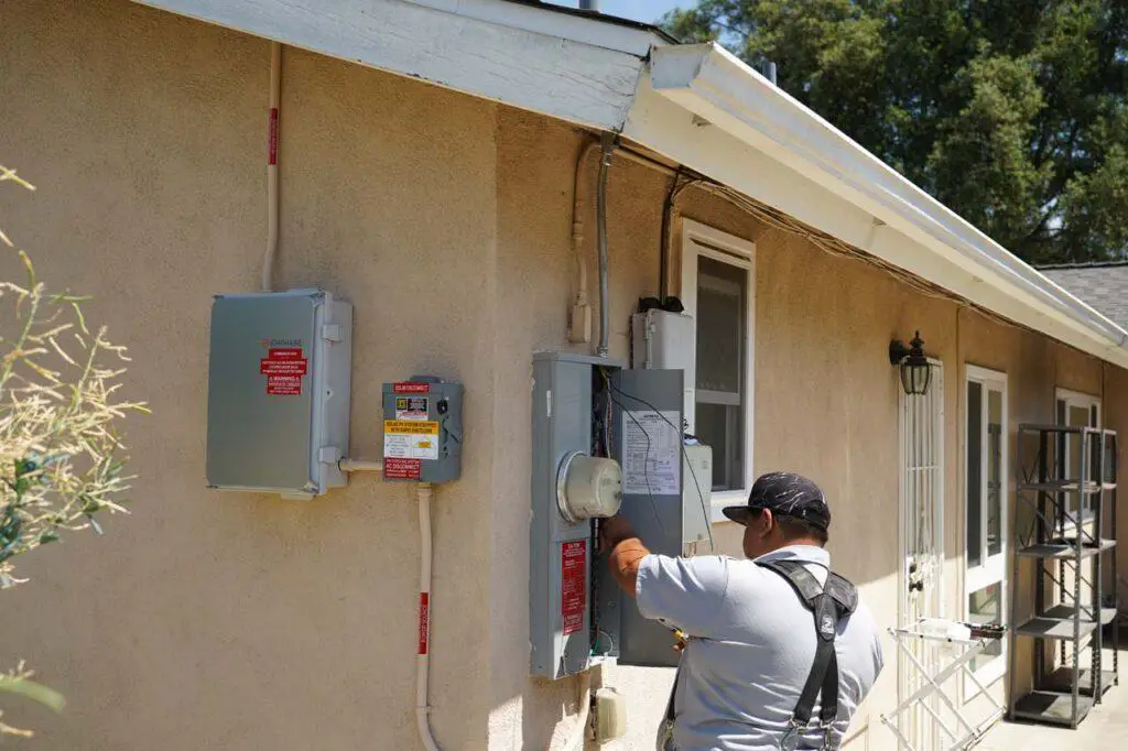 Context of the IQ combiner box with the solar disconnect box, and the upgraded electrical panel, which is adjacent to the utility’s smart meter. The solar panels are on the roof and the electricity generated had to travel all the way to the smart meter to turn it backwards