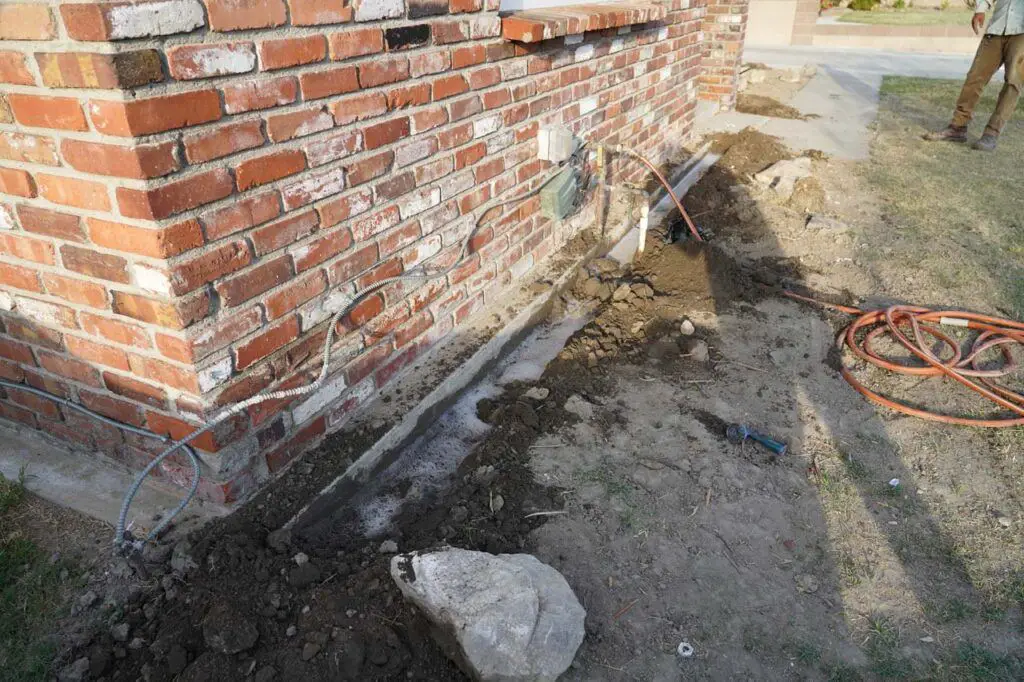 Kenny applying Termidor into the trench that he dug up to try to create a barrier to prevent subterranean termites from invading the wood in the house