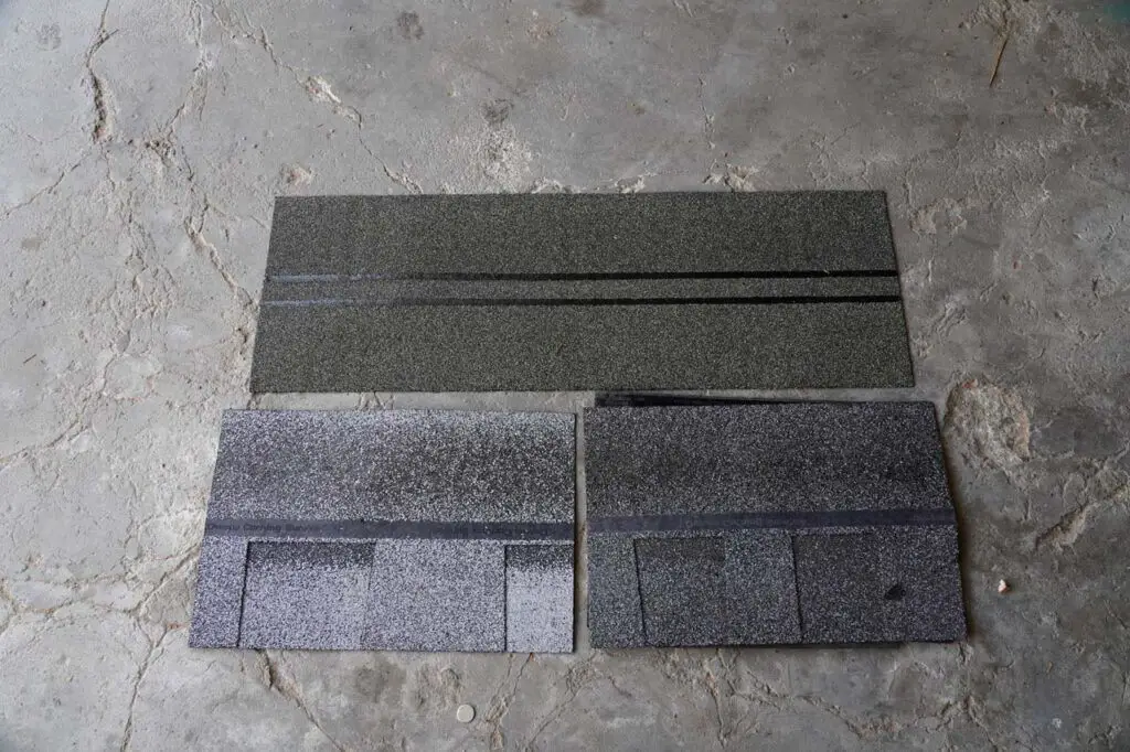 Comparing the Sierra Gray shingles (bottom left) with the Mountainside shingles (bottom right).  The shingle on top was the starter, which is used to reinforce all the vulnerable edges of the roof