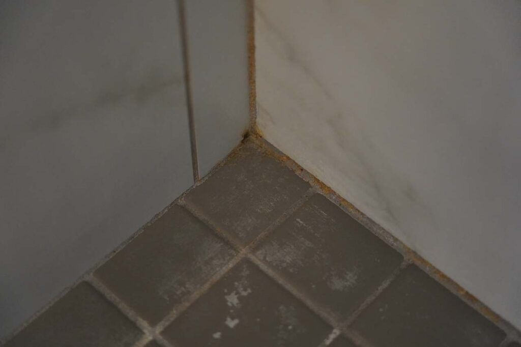 Close-up look at a corner of the shower stall in the rental property, which shows signs of wear but no sign of cracking in the grout