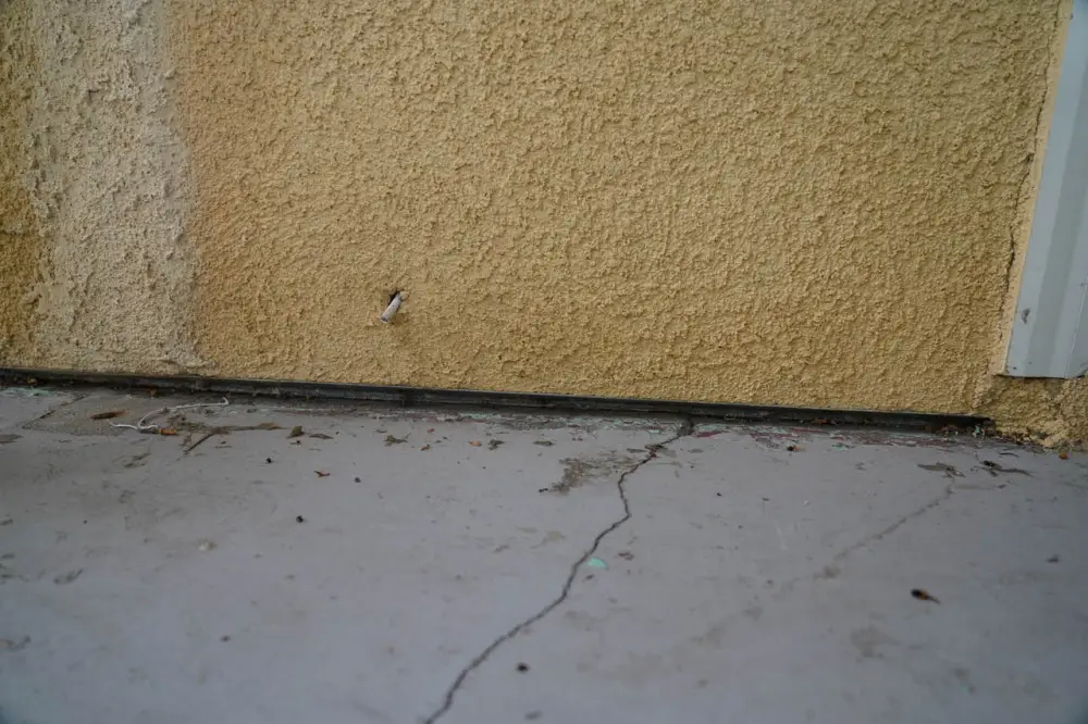The gap between the stucco and the ground is the result of weep screed, which is where water accumulated behind the stucco is allowed to escape and vent or evaporate