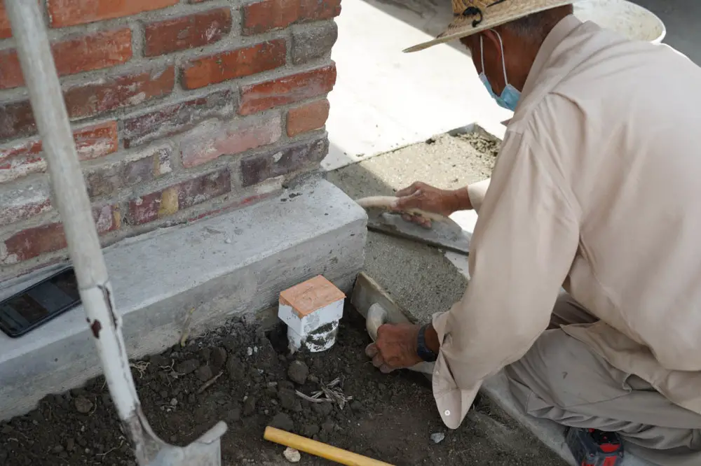 The mason installing a drain and covering its underground piping with concrete