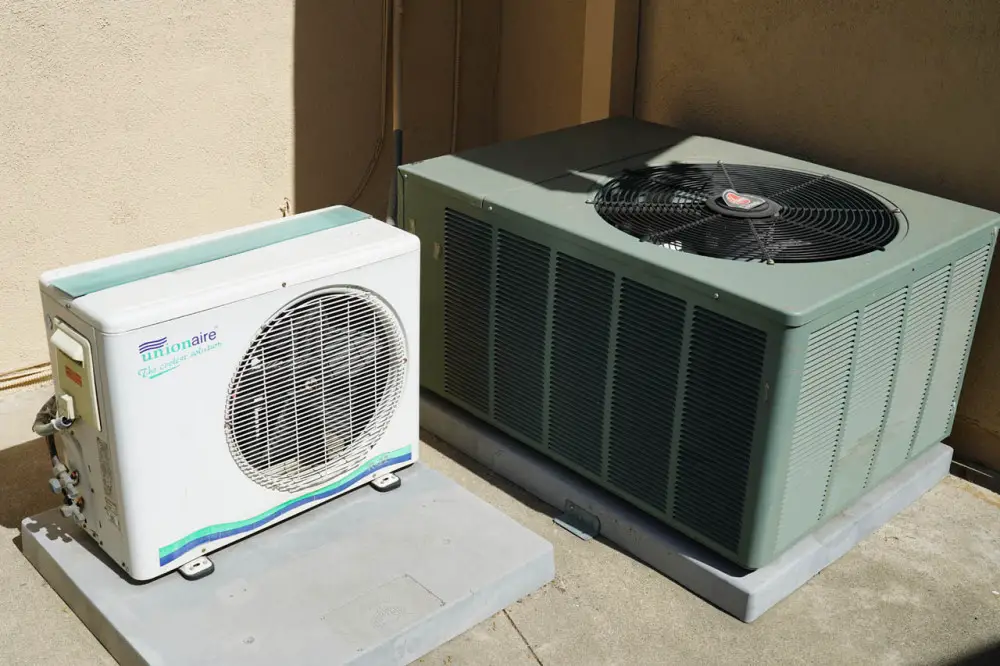 The white unit is the condenser for the room AC while the green unit is the condenser for the central air system